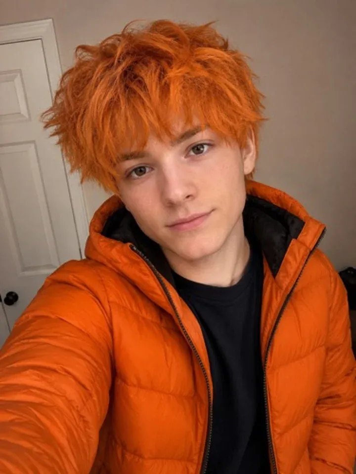 Selfie of a boy with messy red hair in an orange puffer jacket
