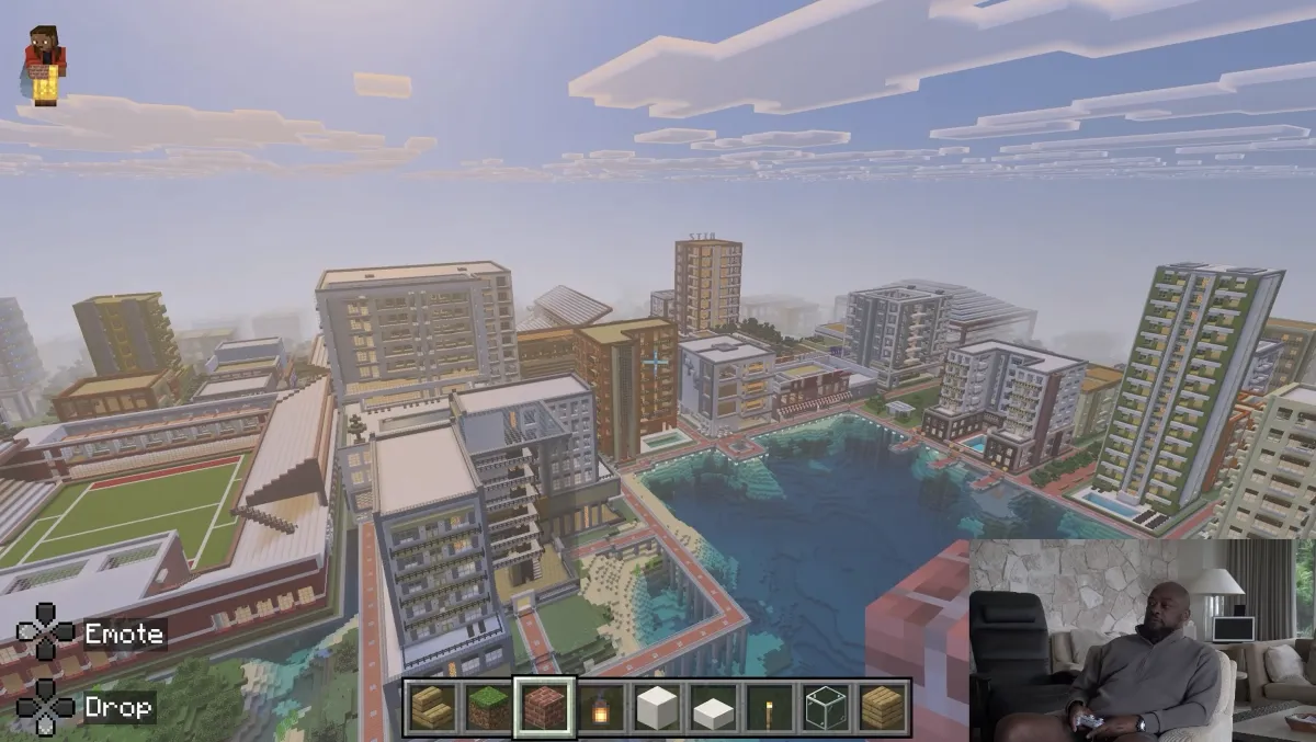 Waterfront skyline of Mike Tomlin's Minecraft city with towers around a central body of water and a sports field